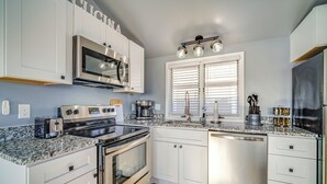 A modern kitchen with white cabinets, stainless steel appliances, and a granite countertop. - Renovated Ocean City Retreat - Walk to Beach! (Ocean City)