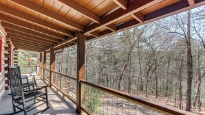 A wooden deck with a rocking chair, overlooking a forested area. - Dog-friendly Hiawassee Cabin Near Lake & Hiking (Hiawassee)