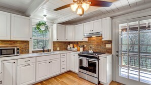 A kitchen with white cabinets, a wooden ceiling, a built-in microwave, and a large window. - Dog-friendly Hiawassee Cabin Near Lake & Hiking (Hiawassee)