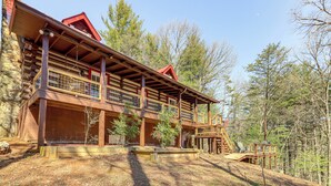 A log cabin with a balcony, wooden deck, and a view of the forest. - Dog-friendly Hiawassee Cabin Near Lake & Hiking (Hiawassee)