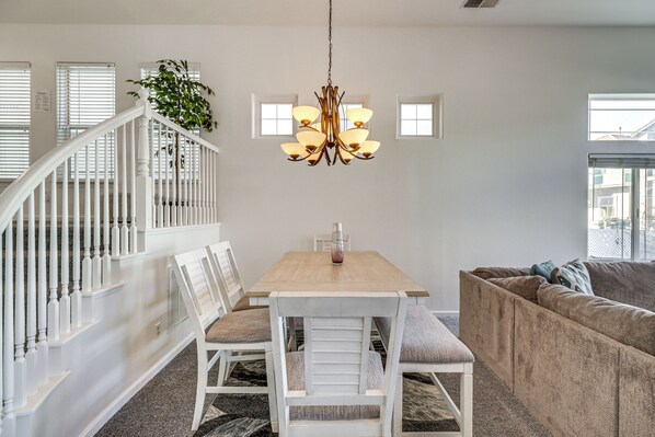A dining area with a wooden table, white chairs, and a chandelier. - Theater Room, Fireplace: Home 5 Mi to Dtwn Reno! (Sparks)
