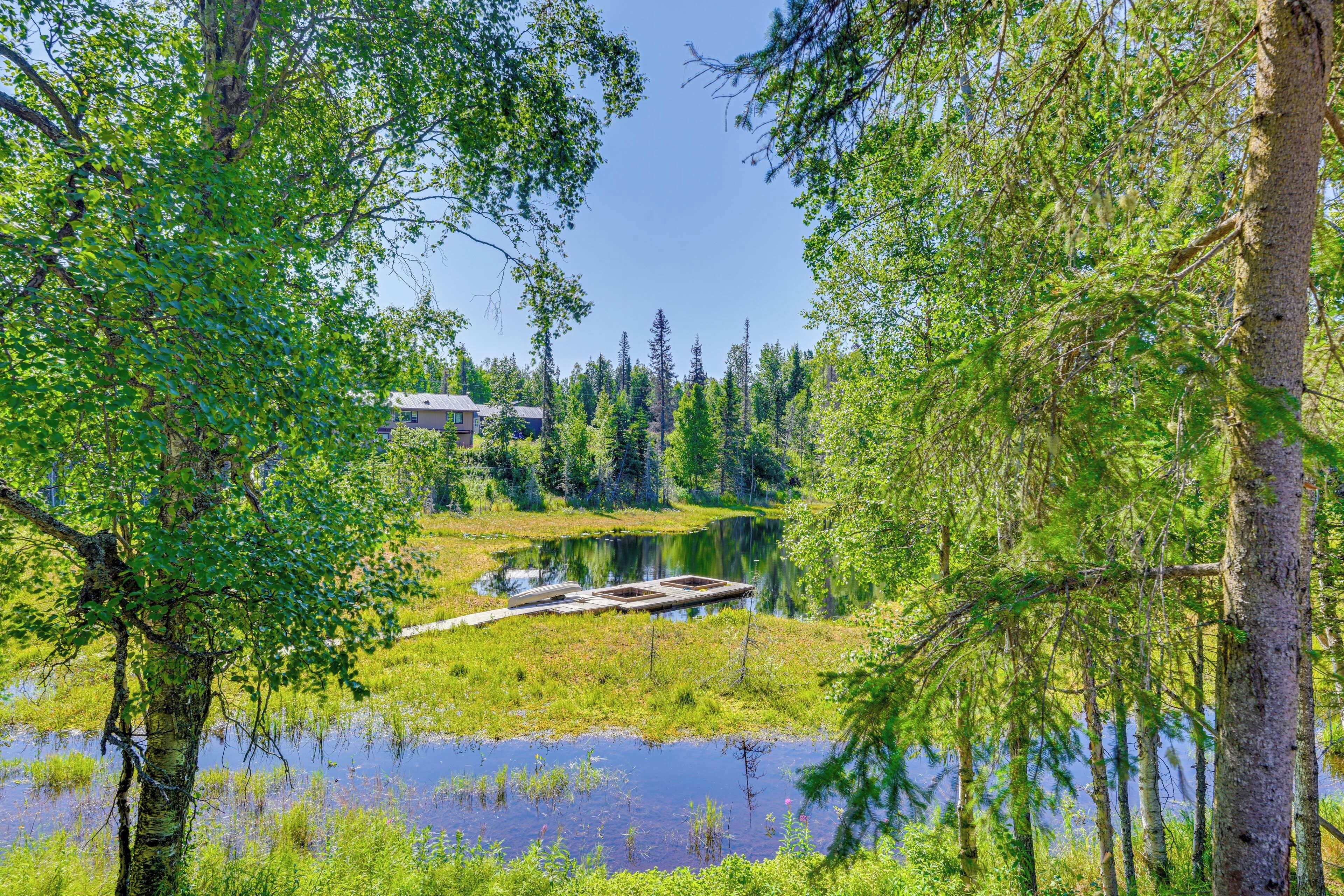 Rantahuvila, jonka laiturilta avautuu näkymä tyynelle järvelle, ja jonka ympärillä on tiheä metsä.