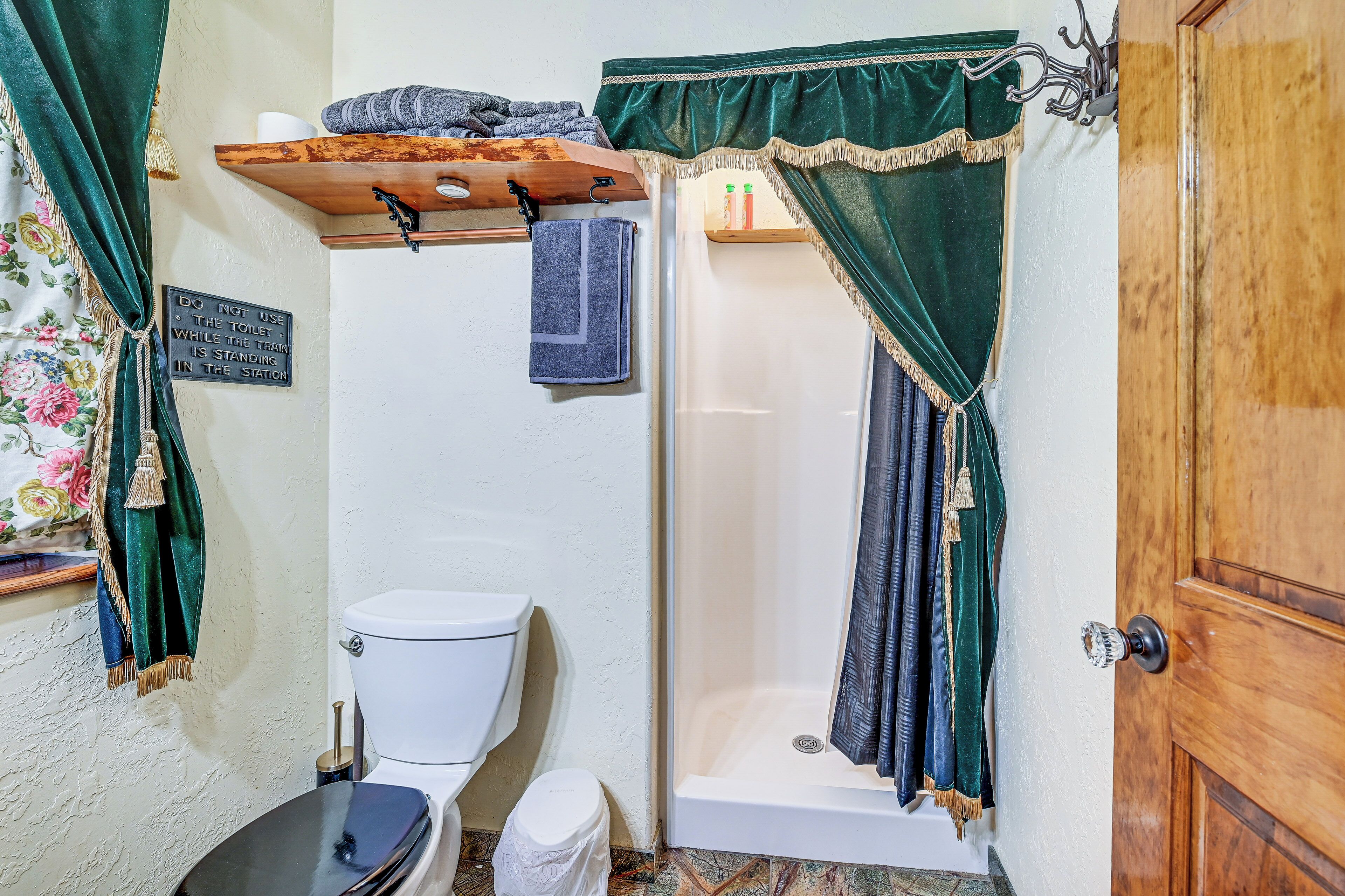 A bathroom with a toilet, shower, and a shelf with towels.