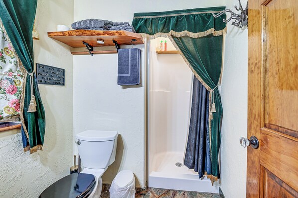 Ein Badezimmer mit Toilette, Dusche und einem Handtuchregal.
