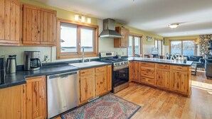 A spacious kitchen with wooden cabinets, a dishwasher, a stove, and a large island. - Delton Lake House w/ Boat Dock: Fish, Swim & More! (Delton)