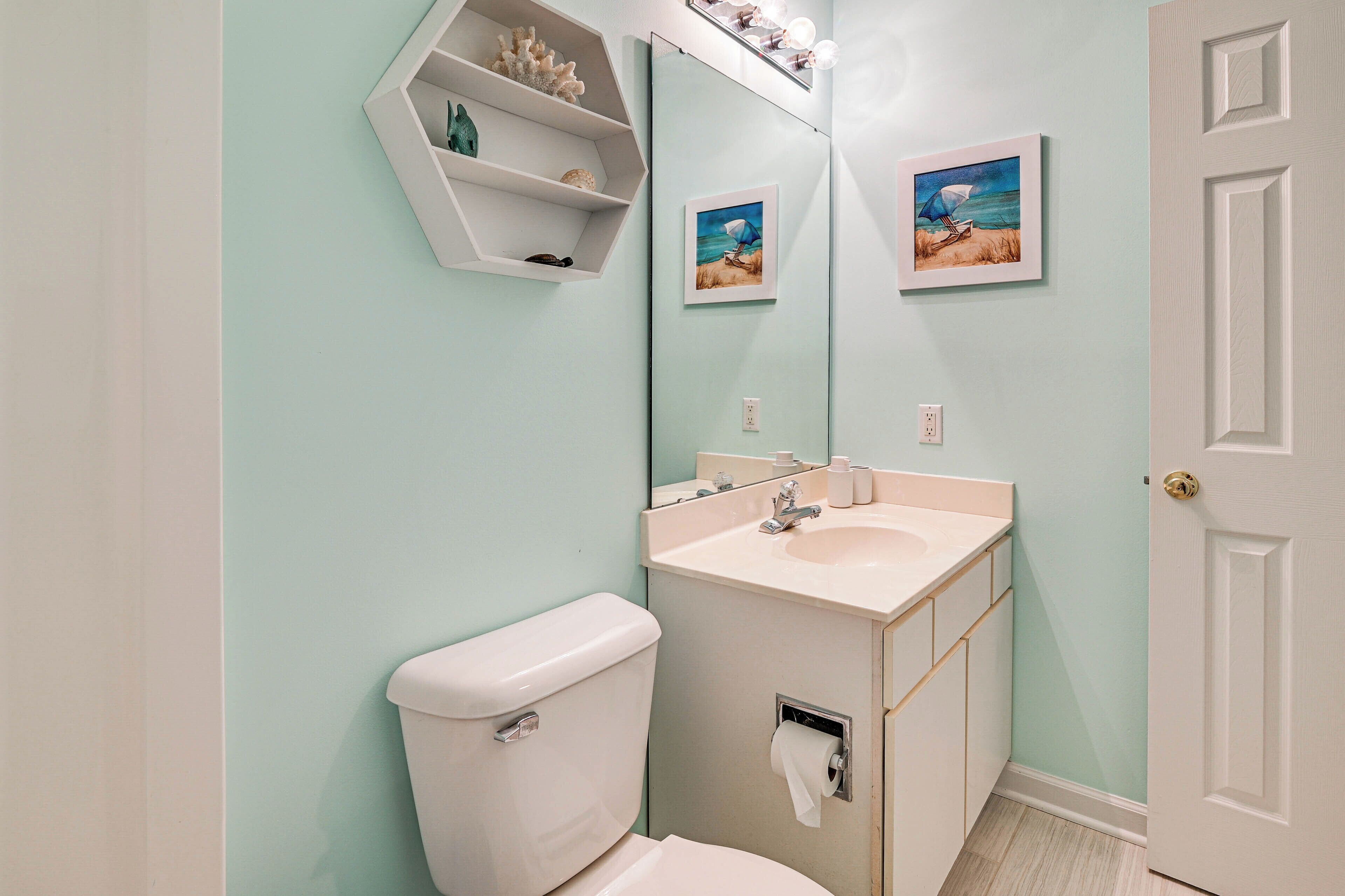 Une salle de bain équipée de toilettes, d’un lavabo et d’une étagère où sont disposés des objets décoratifs.