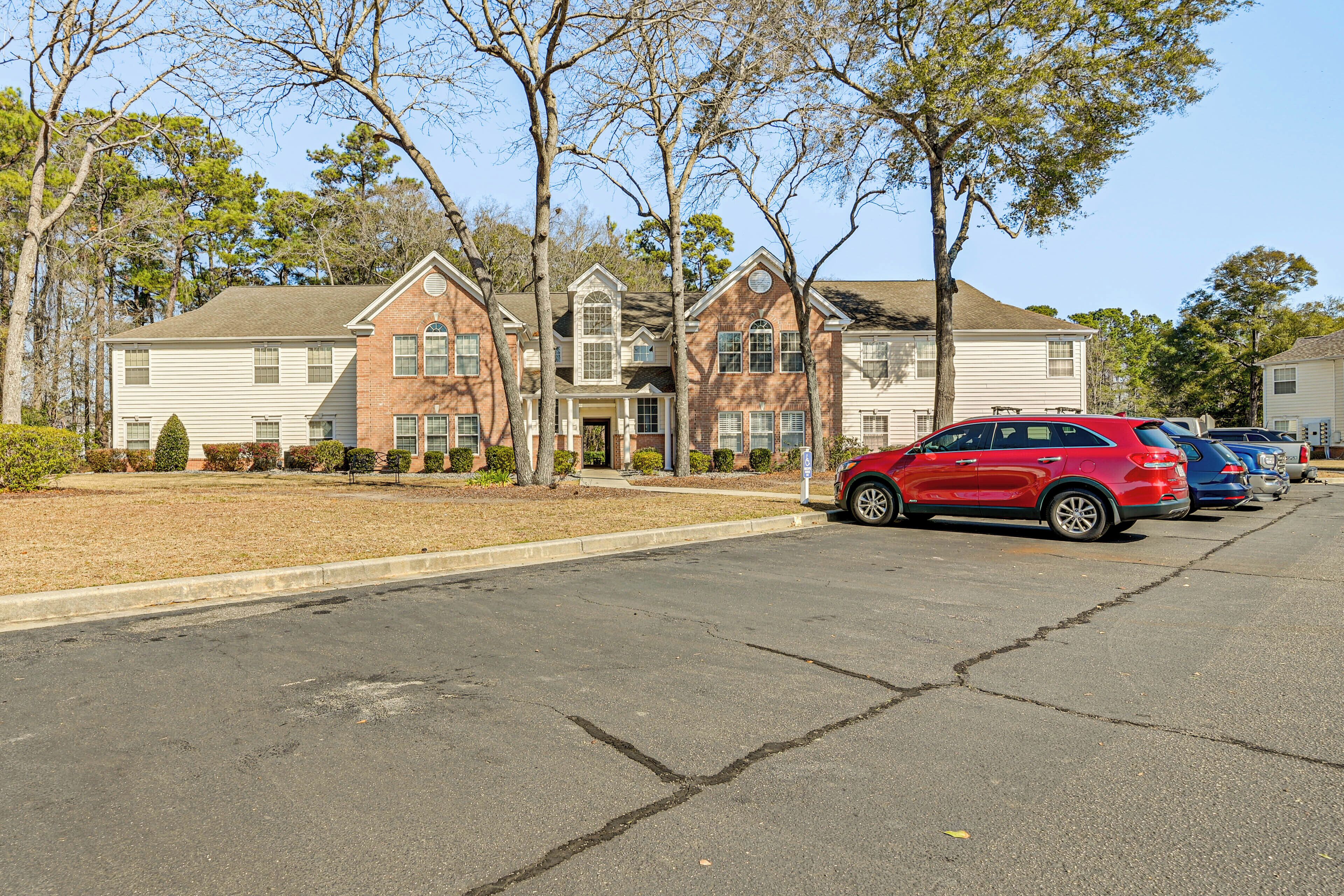 Une rue résidentielle bordée de maisons, avec une voiture rouge garée devant l’une d’elles et une voiture bleue garée devant une autre.