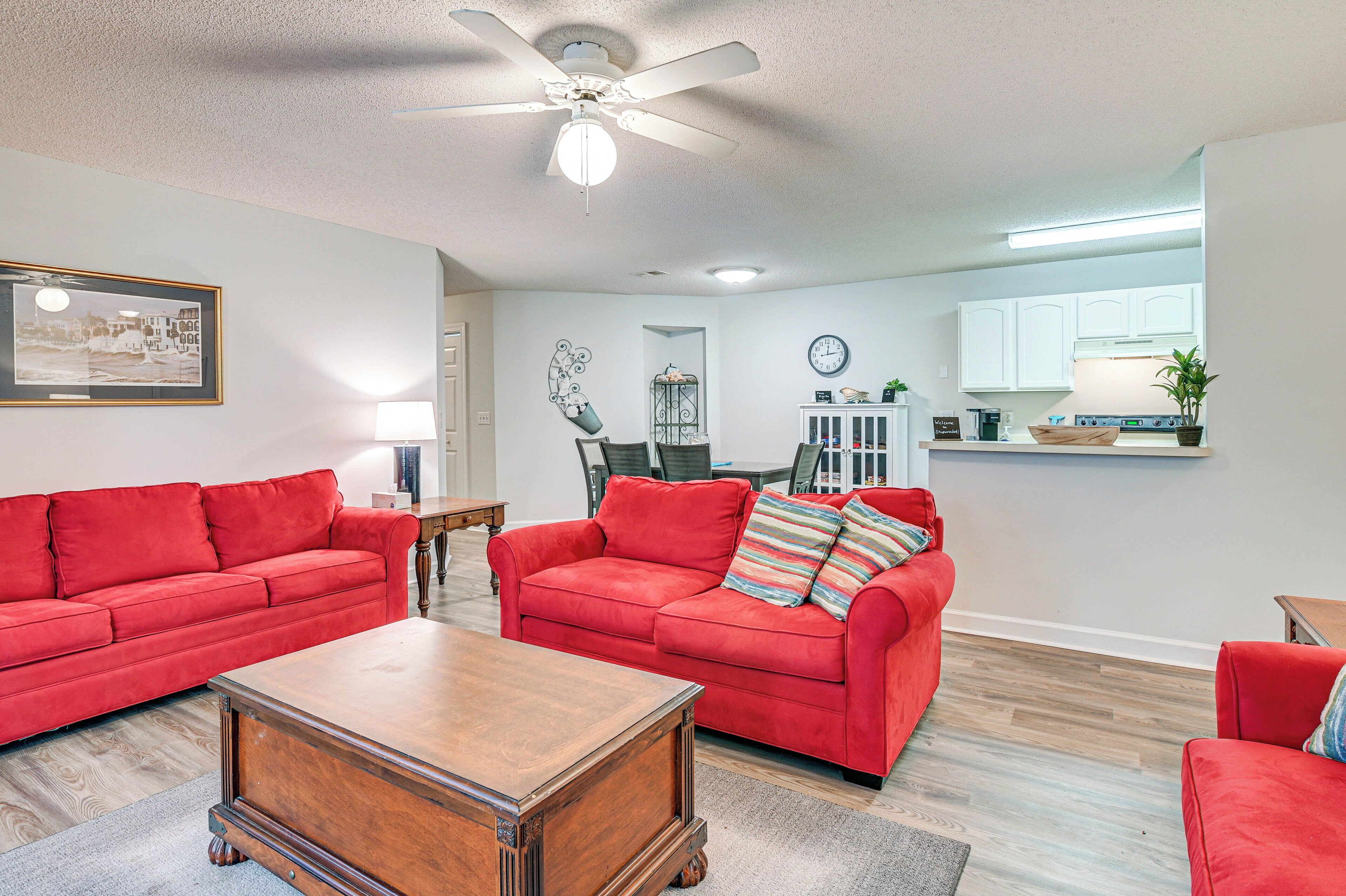 A living room with two red sofas, a wooden coffee table, and a ceiling fan.