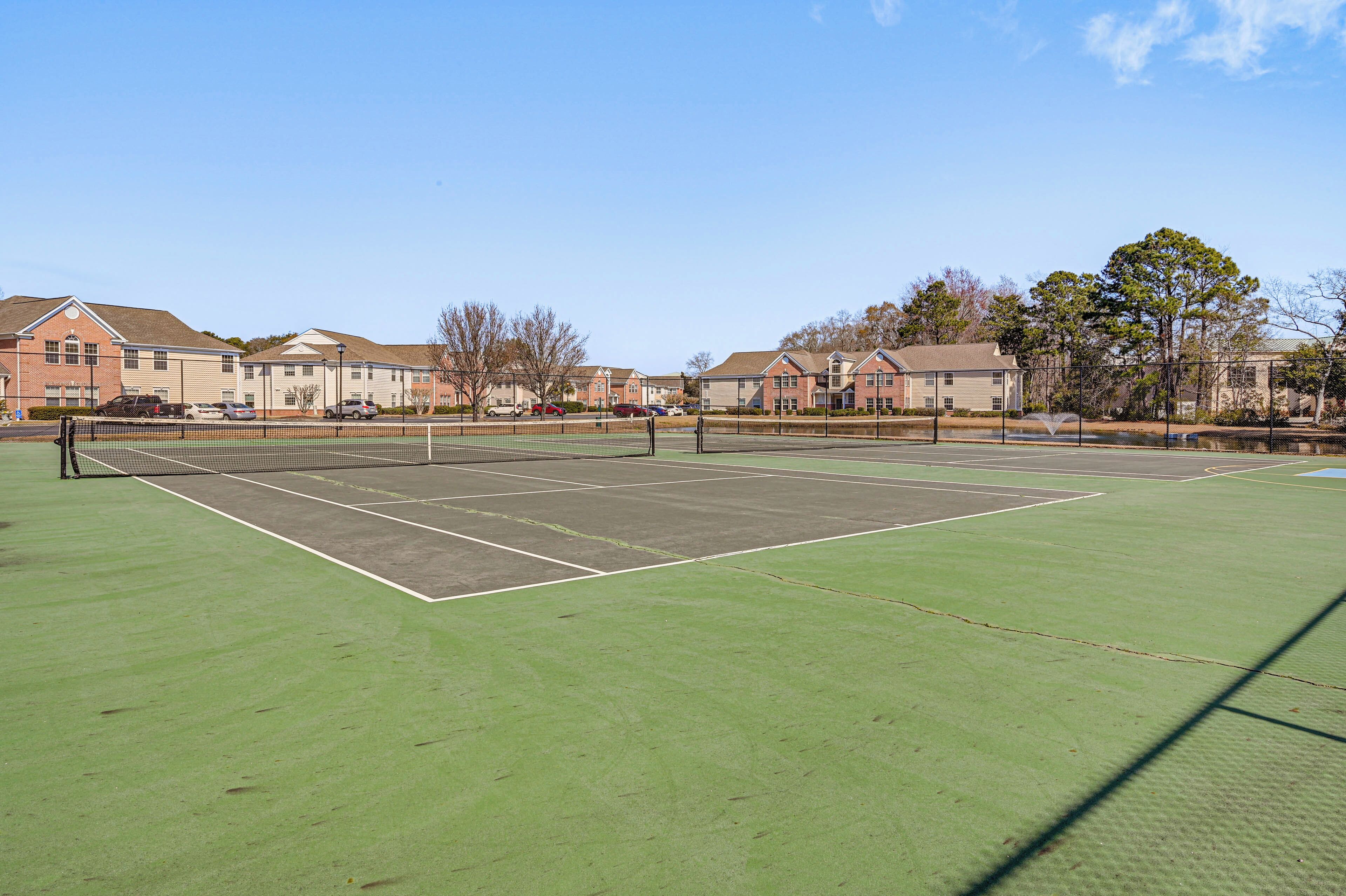 Un court de tennis avec un filet, entouré de bâtiments aux façades en briques et aux fenêtres.