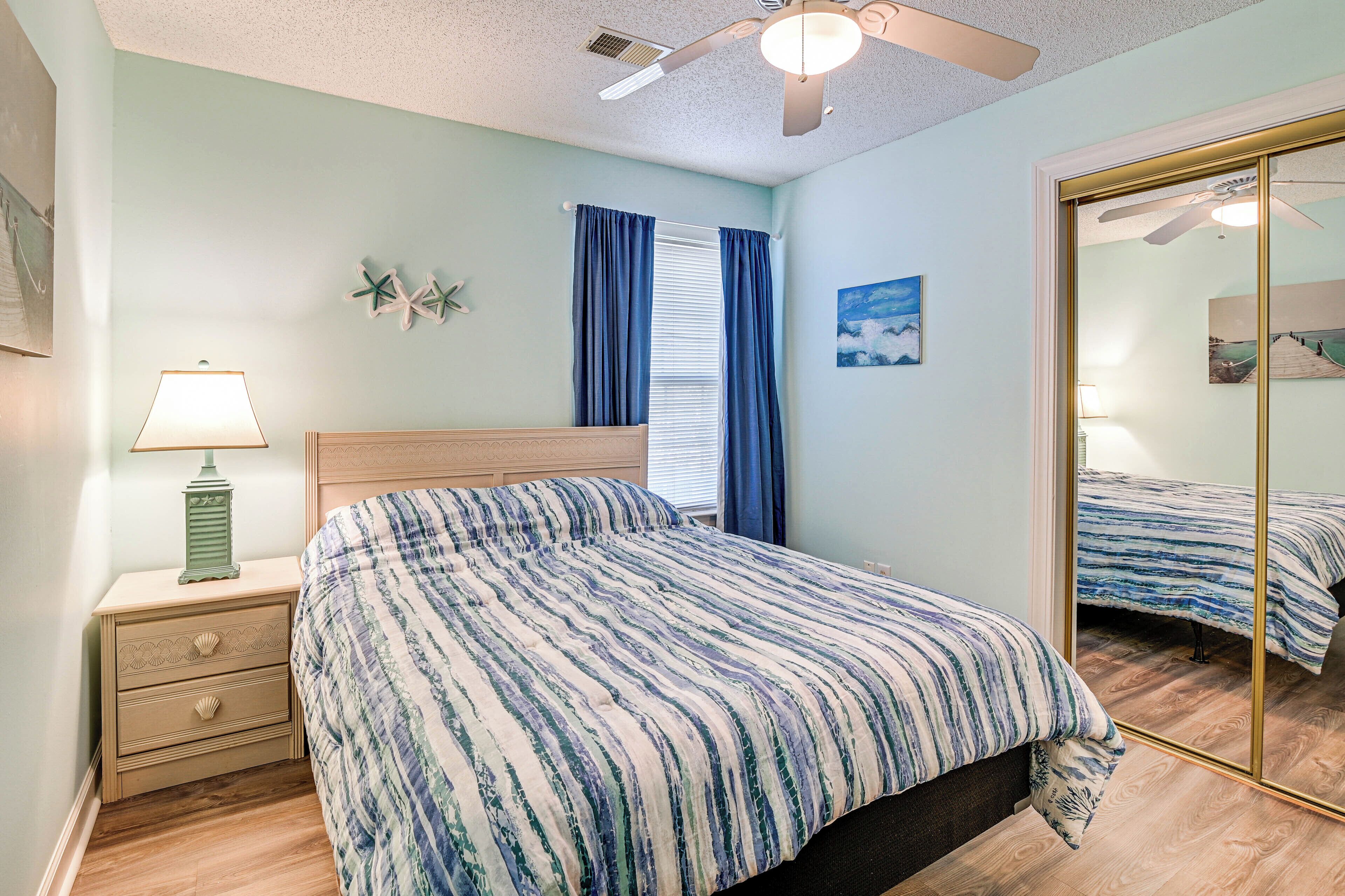 A bedroom with a bed, nightstand, lamp, and a ceiling fan.