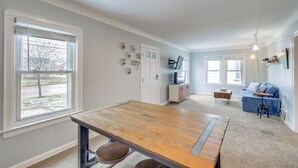 A spacious living area with a large wooden table, a blue sofa, and a TV on a white cabinet. - Wfh-friendly Abode w/ Home Gym in Cleveland (Cleveland)