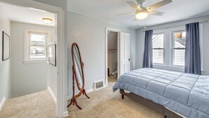 A bedroom with a bed, a ceiling fan, a mirror, and a window with curtains. - Wfh-friendly Abode w/ Home Gym in Cleveland (Cleveland)