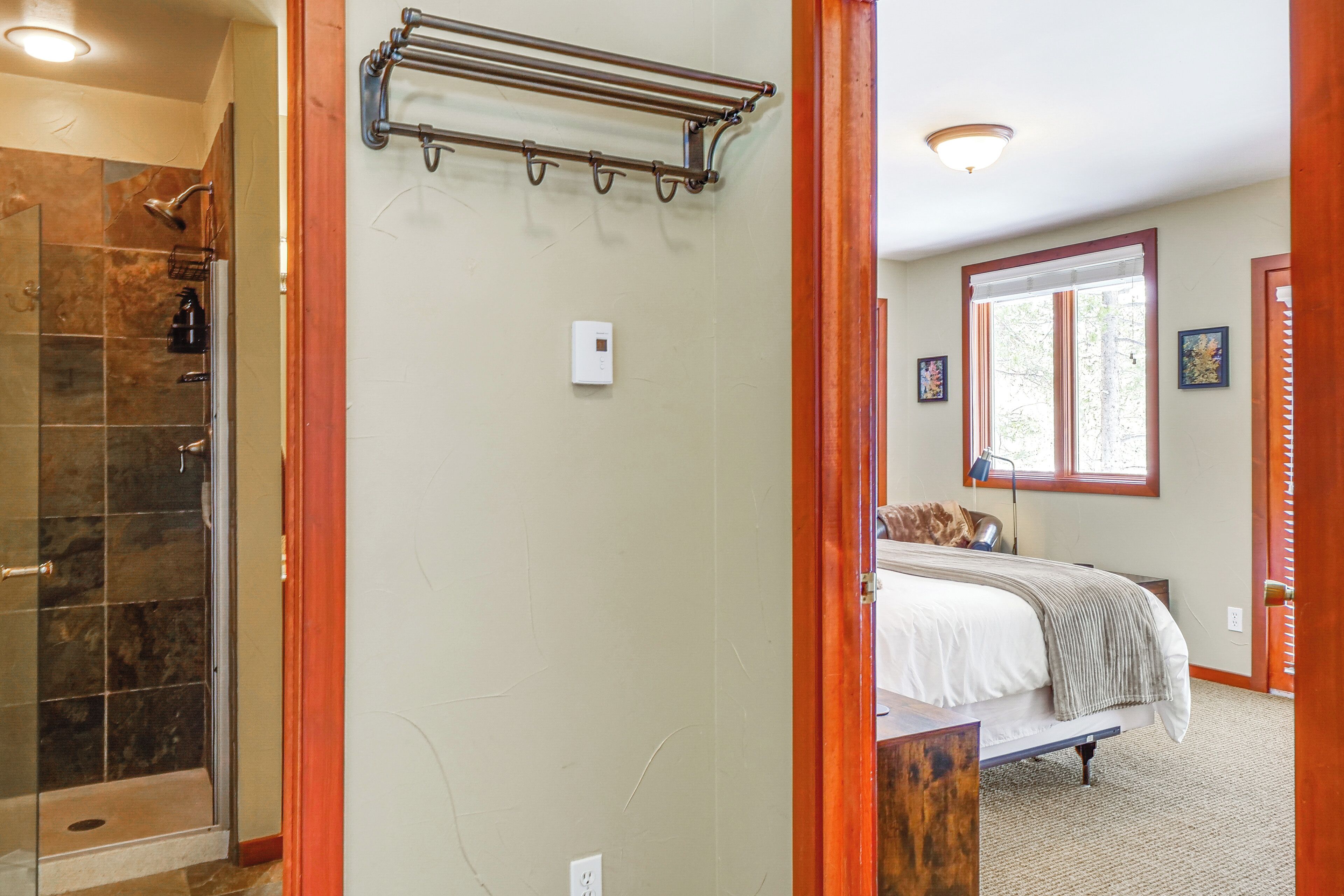 A bathroom with a shower, a towel rack, and a thermostat on the wall.