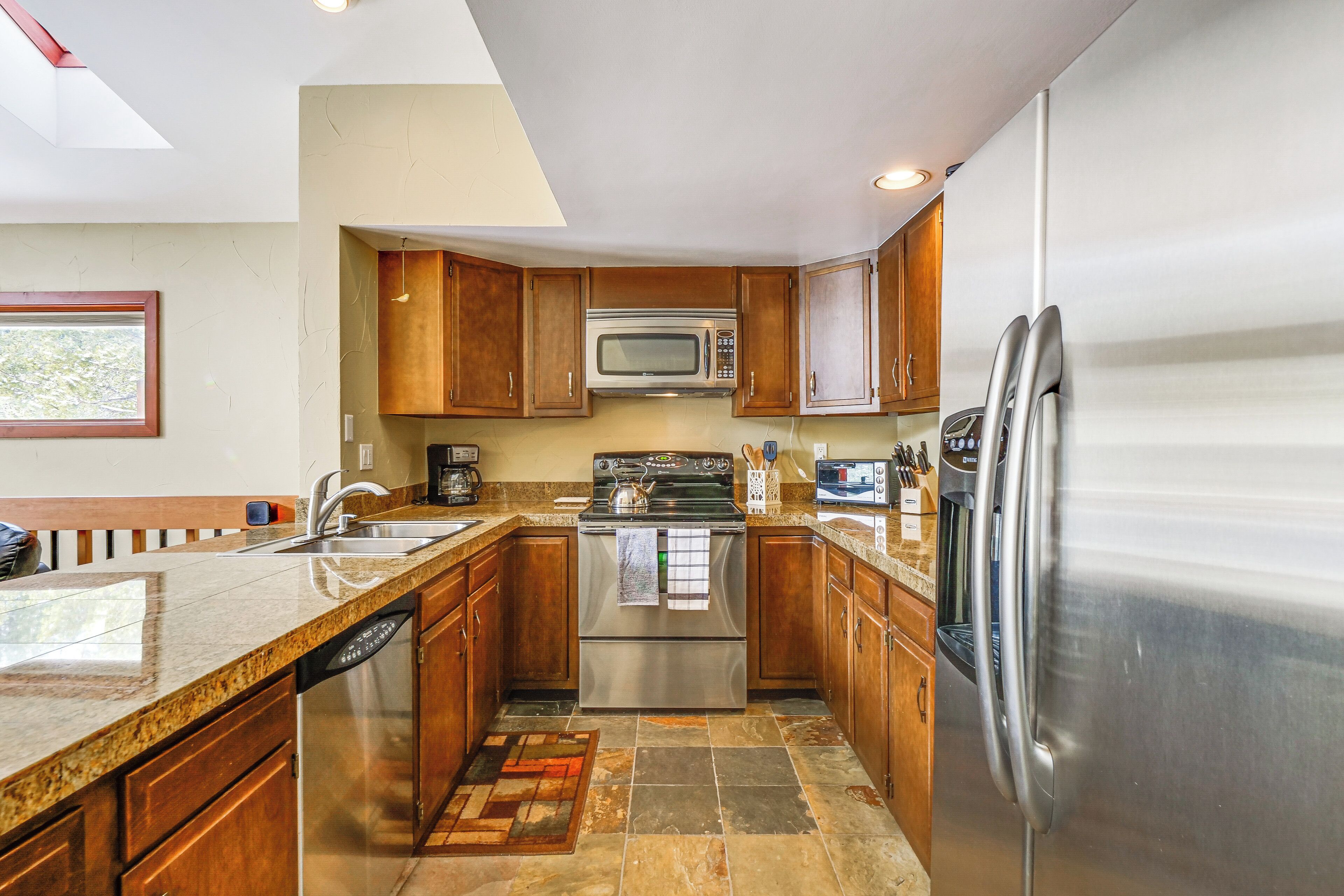 A modern kitchen with granite countertops, stainless steel appliances, and wooden cabinets.