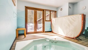 Ein Zimmer mit Holzboden, einem großen Fenster, einer Schiebeglastür und einer Whirlwanne.