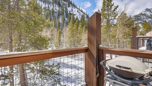 Ein Balkon mit Holzausleger, einem Grill und Blick auf eine verschneite Berglandschaft.