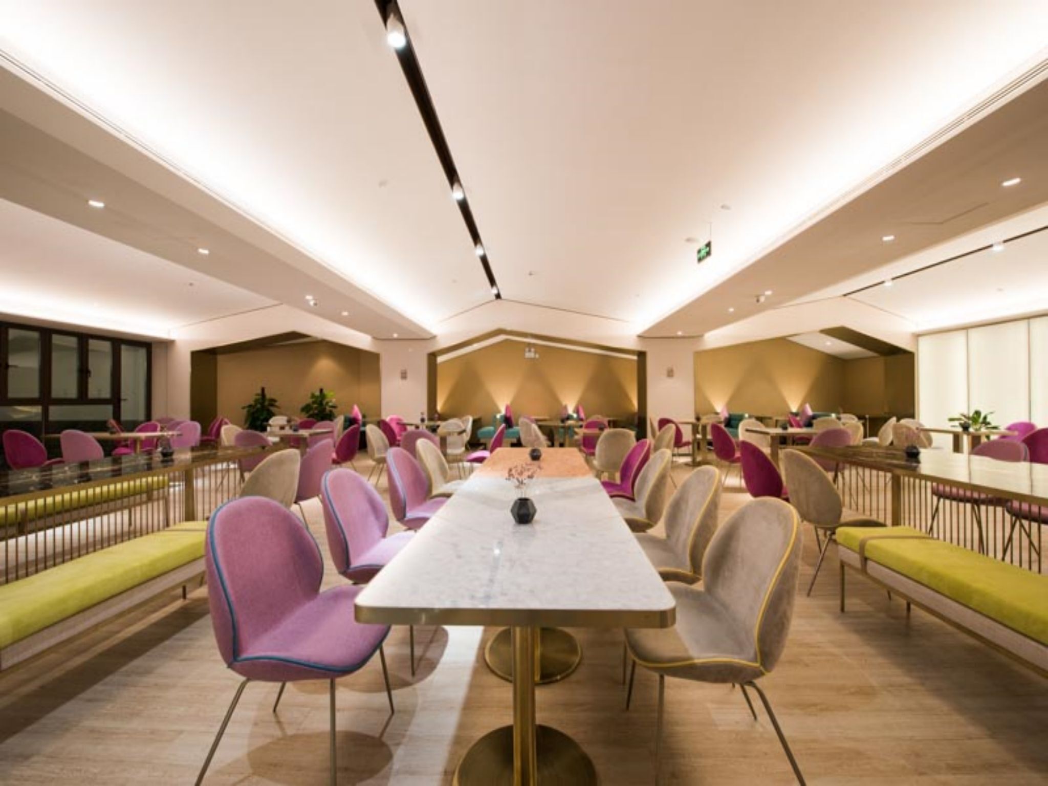 A spacious conference room with a long table and multiple chairs, equipped with a projector and a laptop.