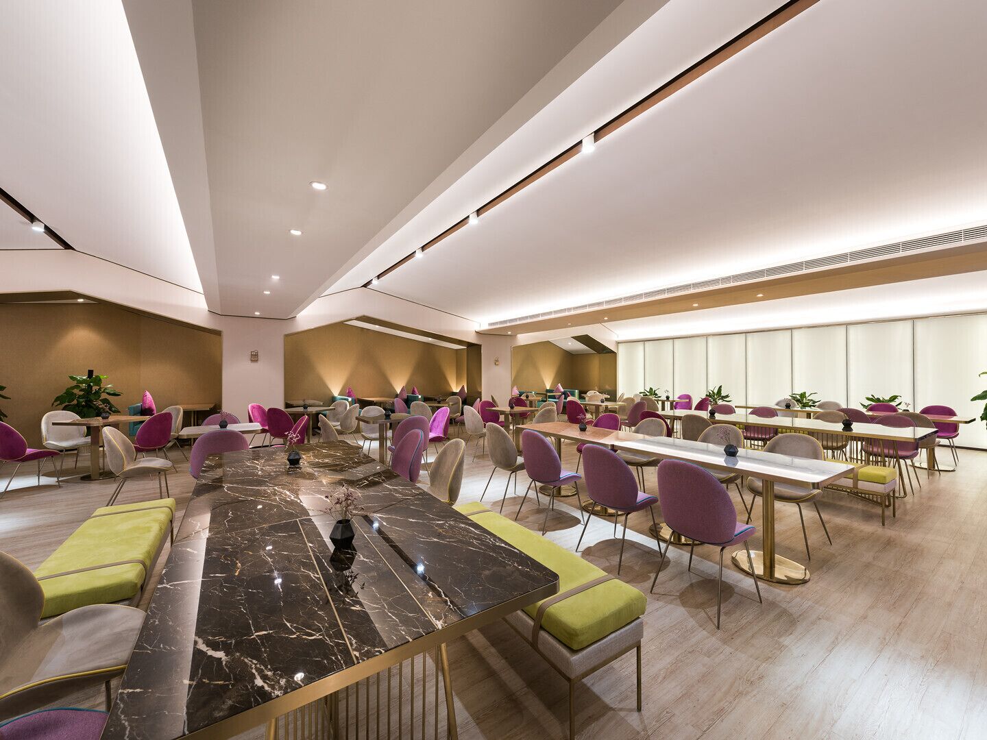 A spacious conference room with a large marble table, multiple chairs, and a modern ceiling design.
