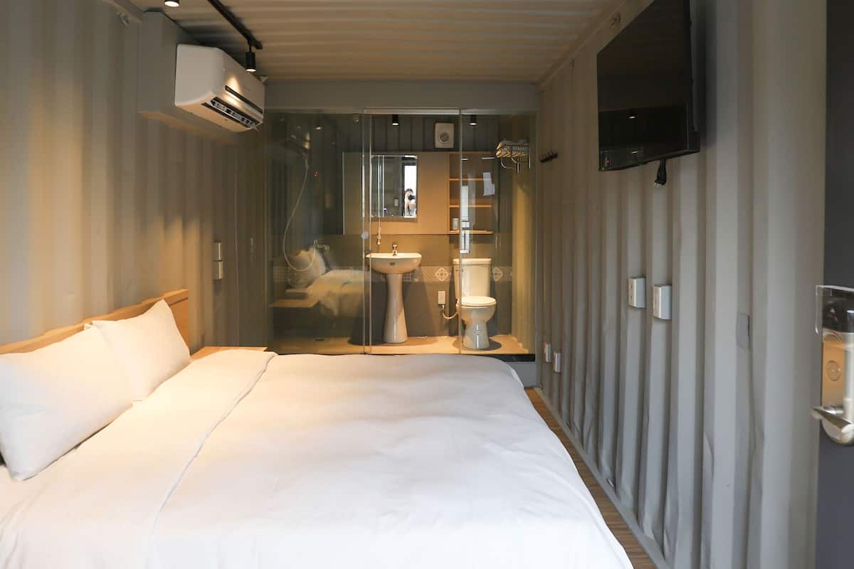 A hotel room with a bed, a sink, and a TV mounted on the wall.