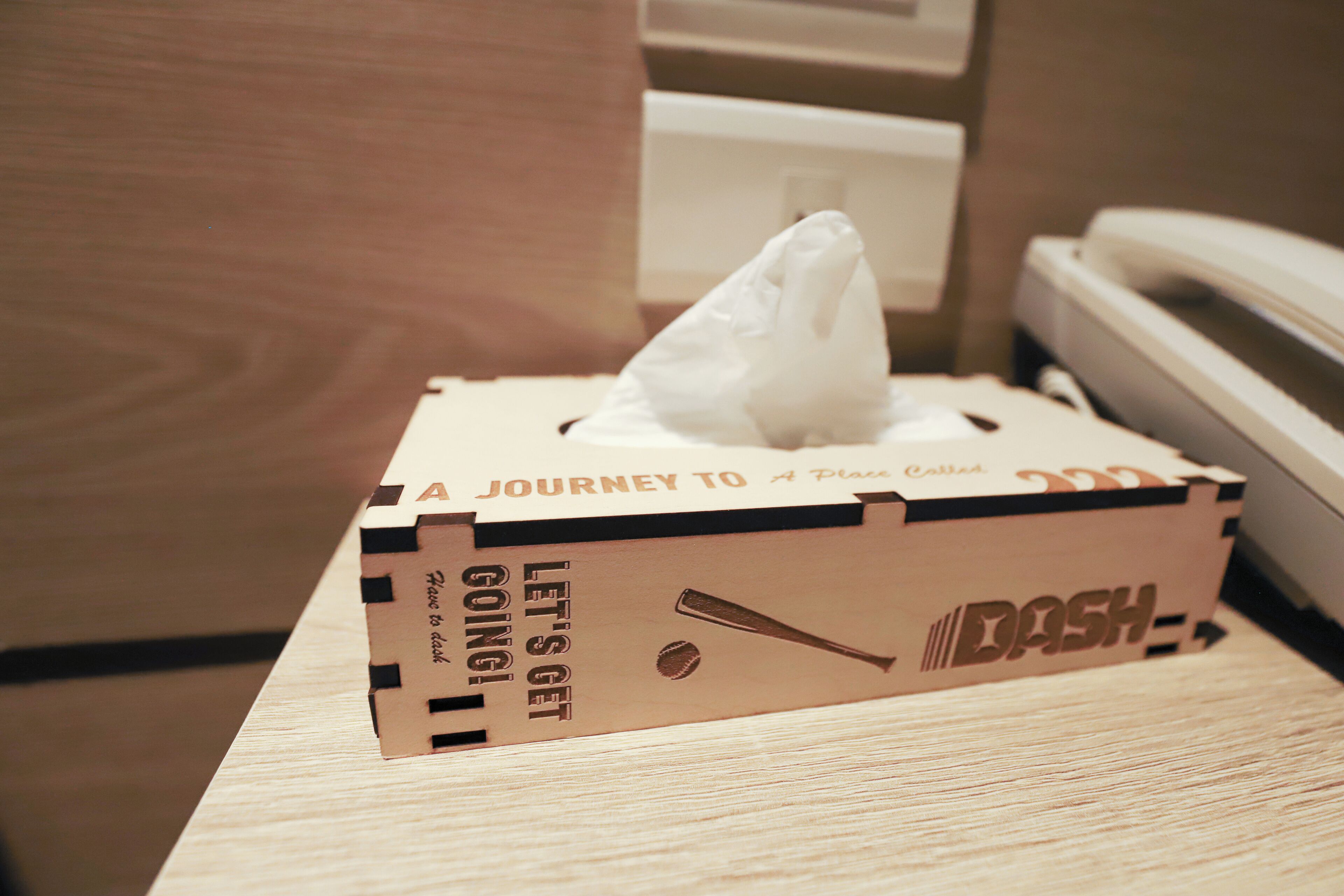 A tissue box on a wooden surface with text and a baseball bat design.