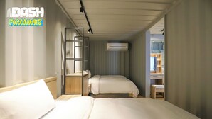 Habitación de hotel con dos camas, un escritorio, un armario y aire acondicionado.
