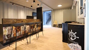 Zona de bar moderna con fondo de madera, un letrero de bienvenida, una escalera y un área de cocina.