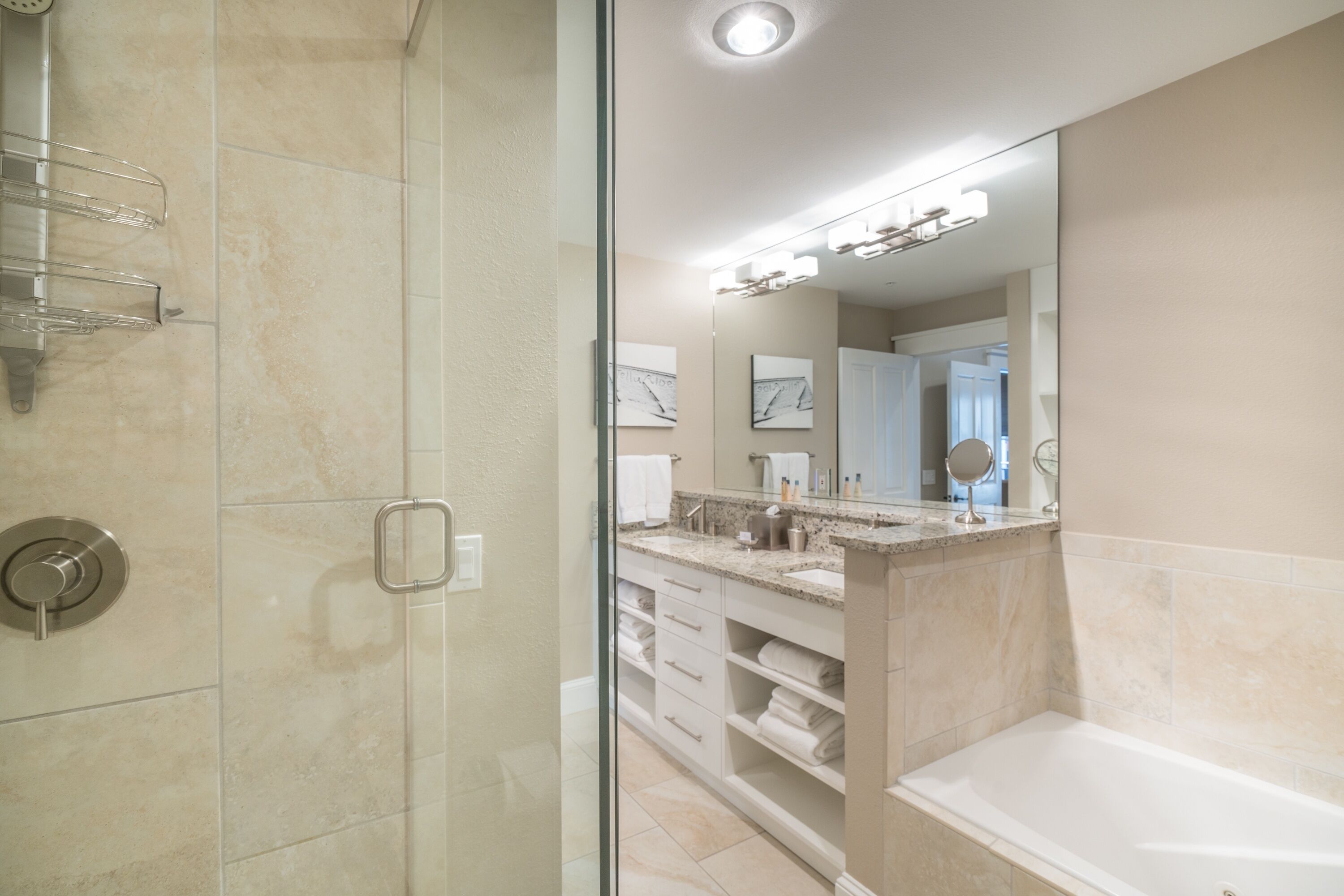 Une salle de bain moderne avec une douche à l’italienne en verre, un grand miroir et une baignoire.