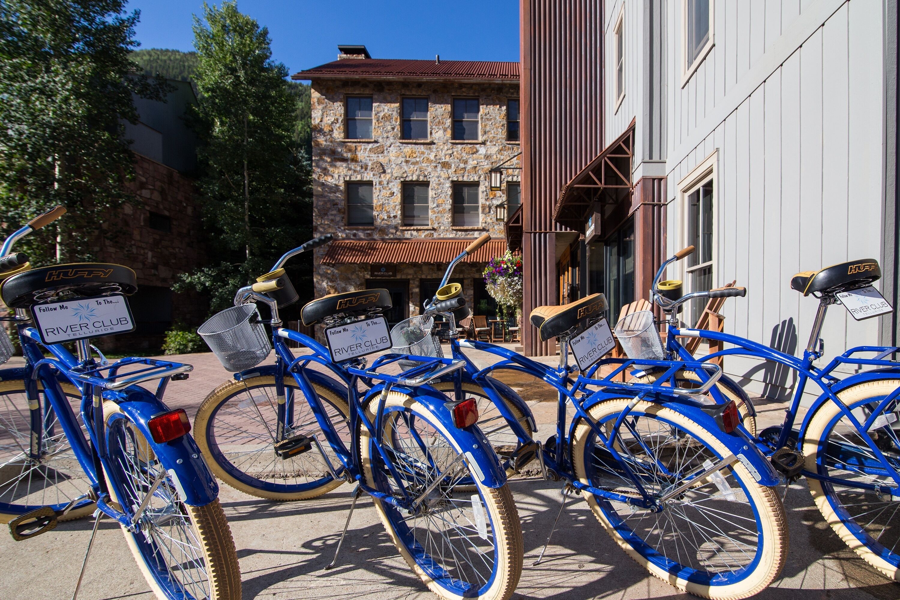 A row of blue bicycles parked in front of a building with a stone facade and a metal awning.