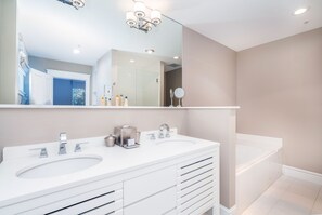 Une salle de bain moderne avec deux lavabos, un grand miroir et une baignoire.