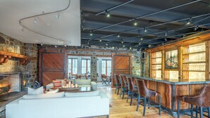 Un vaste espace de vie doté d’une cheminée, d’un bar avec des tabourets et d’un grand canapé.