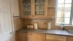 Une cuisine avec des meubles en bois, un plan de travail en granit, un lave-vaisselle Bosch et une fenêtre donnant sur des immeubles.