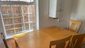 Un coin repas avec une table et des chaises en bois, une fenêtre donnant sur un paysage agréable et un climatiseur blanc fixé au mur.