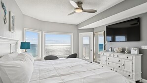 Une chambre à coucher comprenant un lit, un bureau, une chaise, une commode, un téléviseur et un ventilateur de plafond.