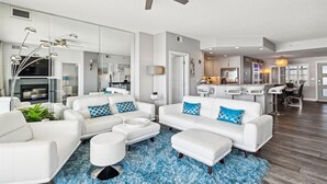 Un salon moderne avec des meubles blancs, un tapis à poils longs bleu et un ventilateur de plafond.