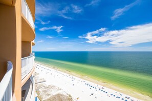 A beachfront hotel balcony with a view of the ocean and beach.