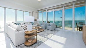 A spacious living room with a large balcony, white sofas, a coffee table, and a rug. - Phoenix Gulf Towers 2104 4 Bedroom Condo (Orange Beach)