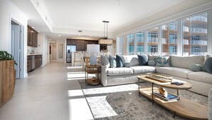 A spacious living room with a large sofa, a coffee table, and a dining area with a table and chairs. - Phoenix Gulf Towers 2104 4 Bedroom Condo (Orange Beach)