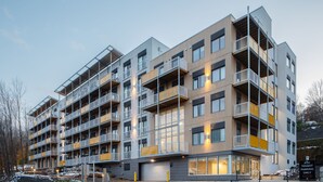 Een meerlaags appartementencomplex met balkons, een garage-ingang en een bordje met de tekst 'Alleen bewoners parkeren'.