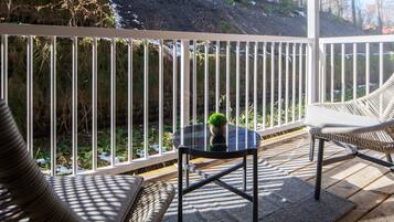 Un balcon avec une table en verre, une chaise en osier et une balustrade blanche.