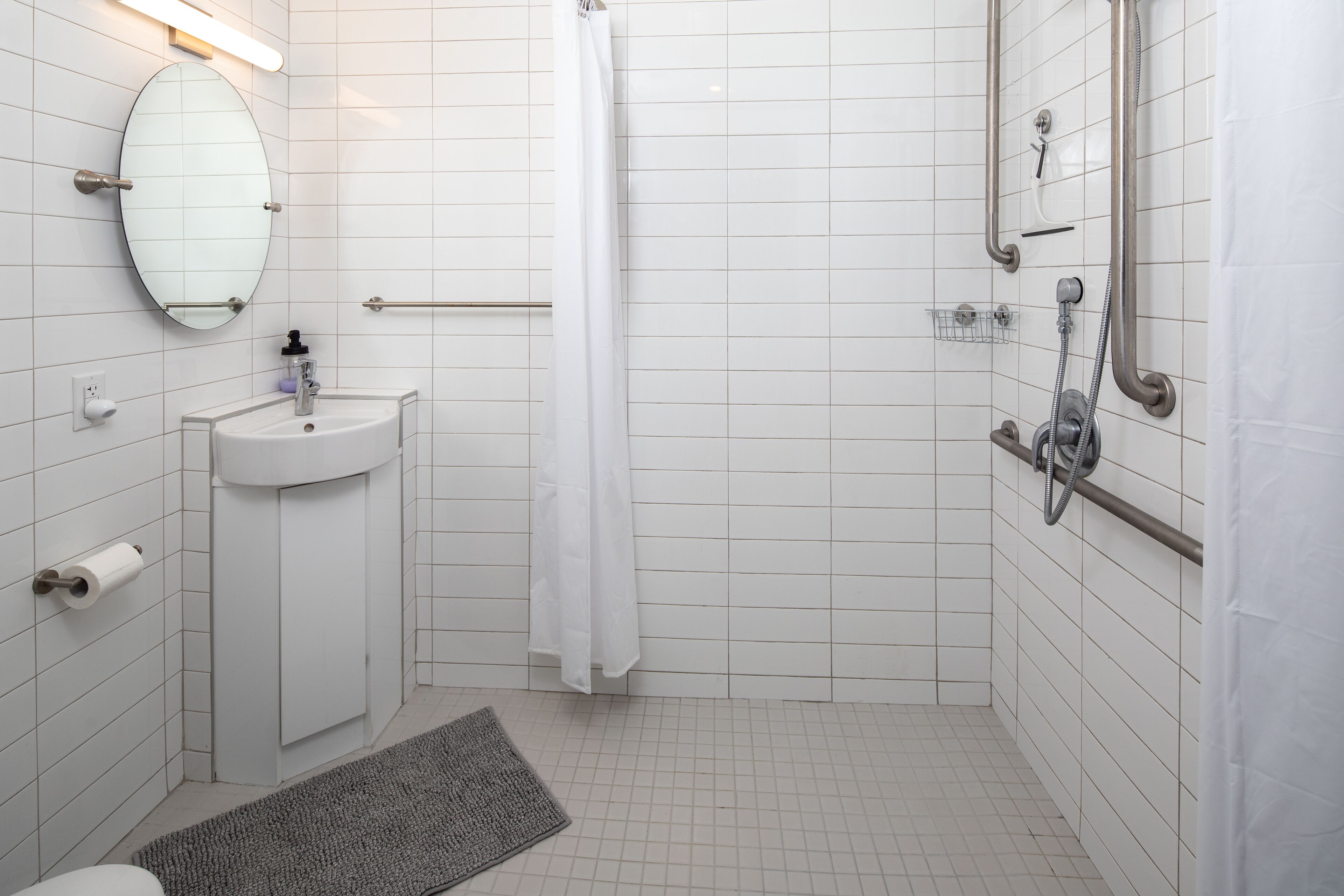 Une salle de bain équipée d’un lavabo, d’un miroir, d’une douche et de toilettes.