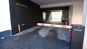 Ein begrenzter Eingangsbereich mit einer schwarzen Mauer und einem Schild mit der Aufschrift 'ALTE STR.9-10'.