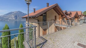 A row of chalet-style buildings with balconies overlooking a lake and mountains. - Veloccino del Lago in Perledo (Perledo)