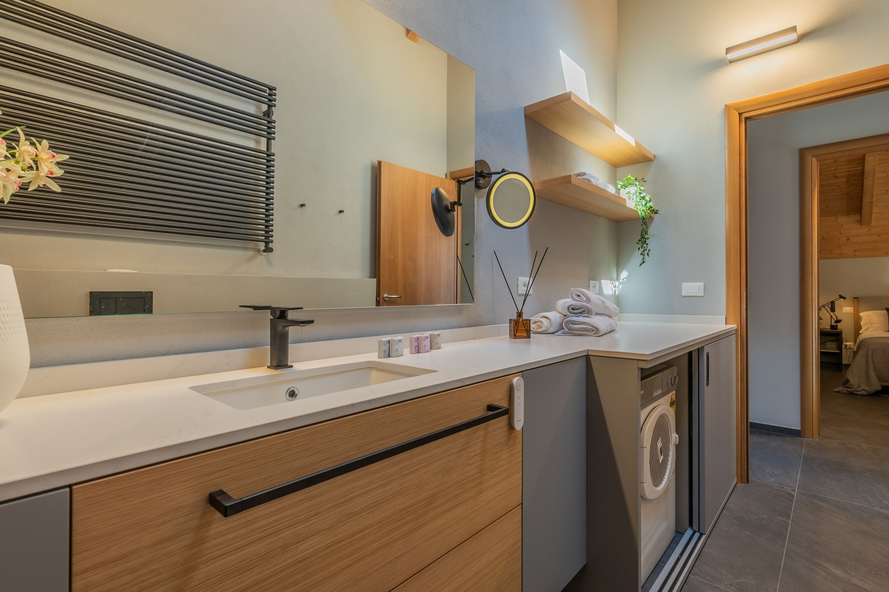 A modern bathroom with a sink, mirror, towel rack, and a built-in washing machine.