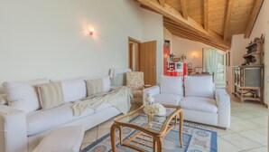 A living room with a wooden ceiling, white sofas, a glass coffee table, and a patterned rug. - Veloccino del Lago in Perledo (Perledo)