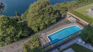 An aerial view of a swimming pool surrounded by trees, with a view of the sea in the background. - Veloccino del Lago in Perledo (Perledo)