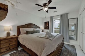 Une chambre à coucher avec un lit en bois, un ventilateur de plafond, une table de chevet et une vue sur l’extérieur par une fenêtre.