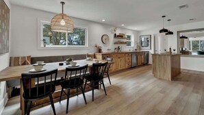 Una cocina moderna con una mesa de comedor de madera, sillas negras e iluminación colgante.