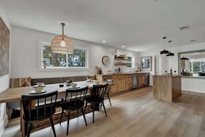 Una cocina moderna con una mesa de comedor de madera, sillas negras e iluminación colgante.