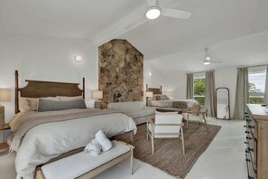 A spacious bedroom with a large bed, a smaller bed, and a seating area. There is a stone accent wall and a view of the outdoors. - Grasslands: Pool+Hot-Tub+Views on 290 Wine Trail! (Johnson City)