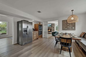 A modern kitchen with a large refrigerator, wooden cabinets, and a dining area with a wooden table and chairs.
